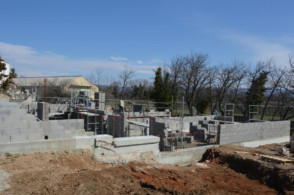 Outdoor construction site showing cinder block walls and scaffolding under a clear sky.